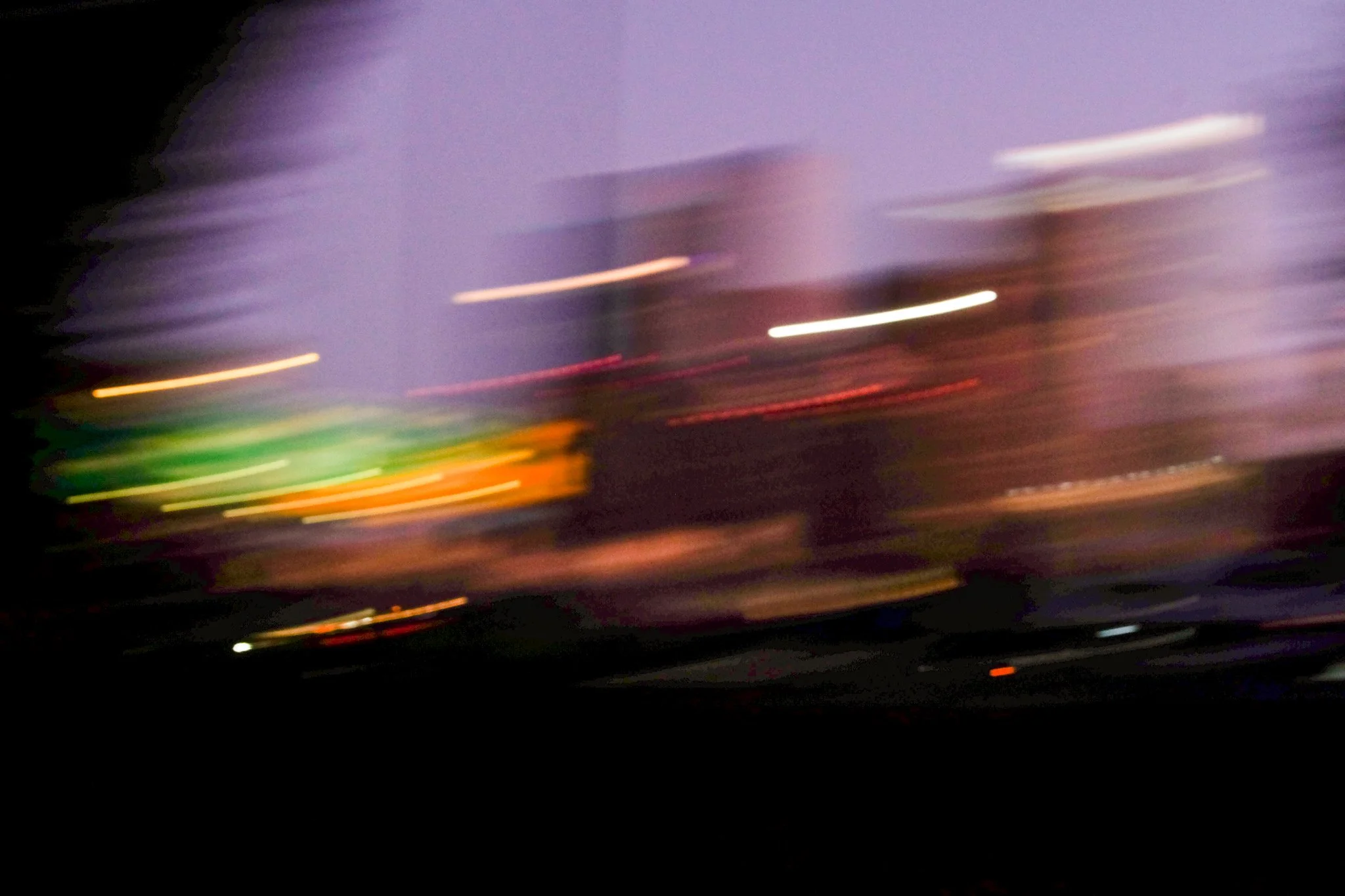 Blurred night scene with streaks of colorful light, possibly from moving vehicles or city lights.