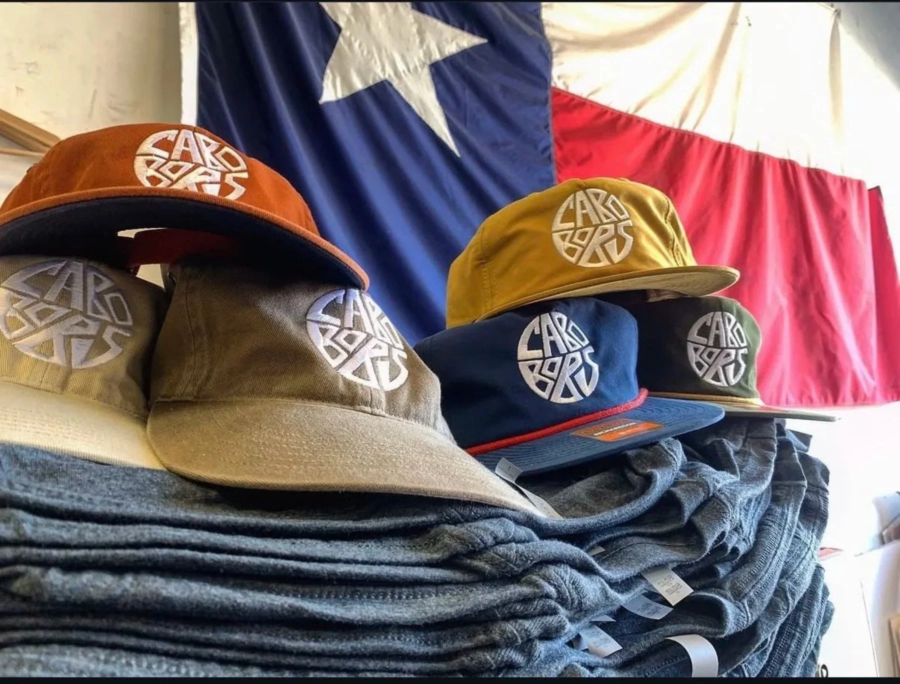 Custom Embroidered hats and screen printed shirts stacked on each other for Cabo Bob's Texas Business.