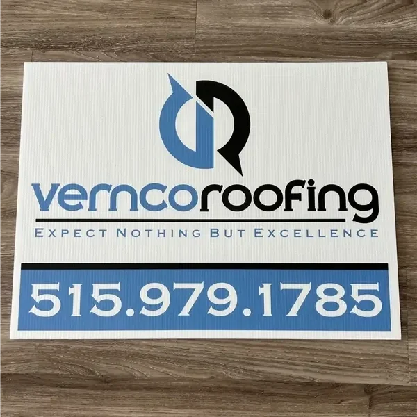 A white sign with a logo of overlapping blue and black shapes, the text 'vermc roofing' in blue and black, the slogan 'EXPECT NOTHING BUT EXCELLENCE' in blue, and a large phone number '515.979.1785' in white on a blue background.