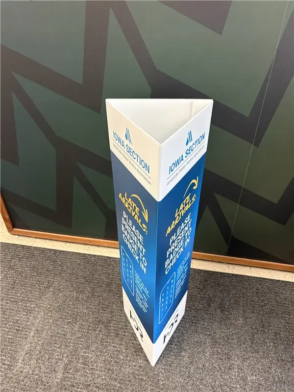 A blue and white standing sign for Iowa Section with instructions to please lift and proceed to check-in.