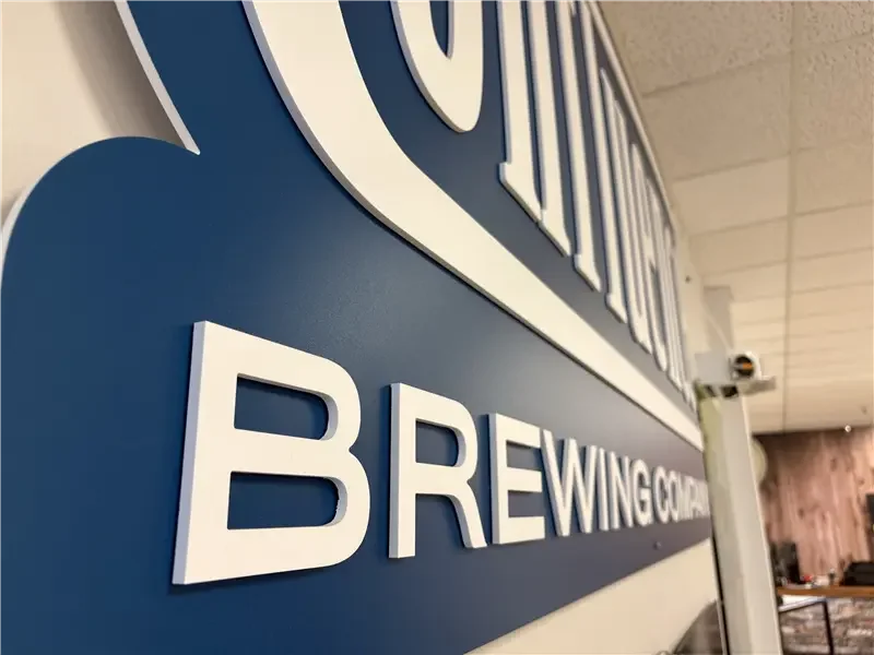 Close-up of a sign reading 'BREWingCo' in large white letters on a blue background.