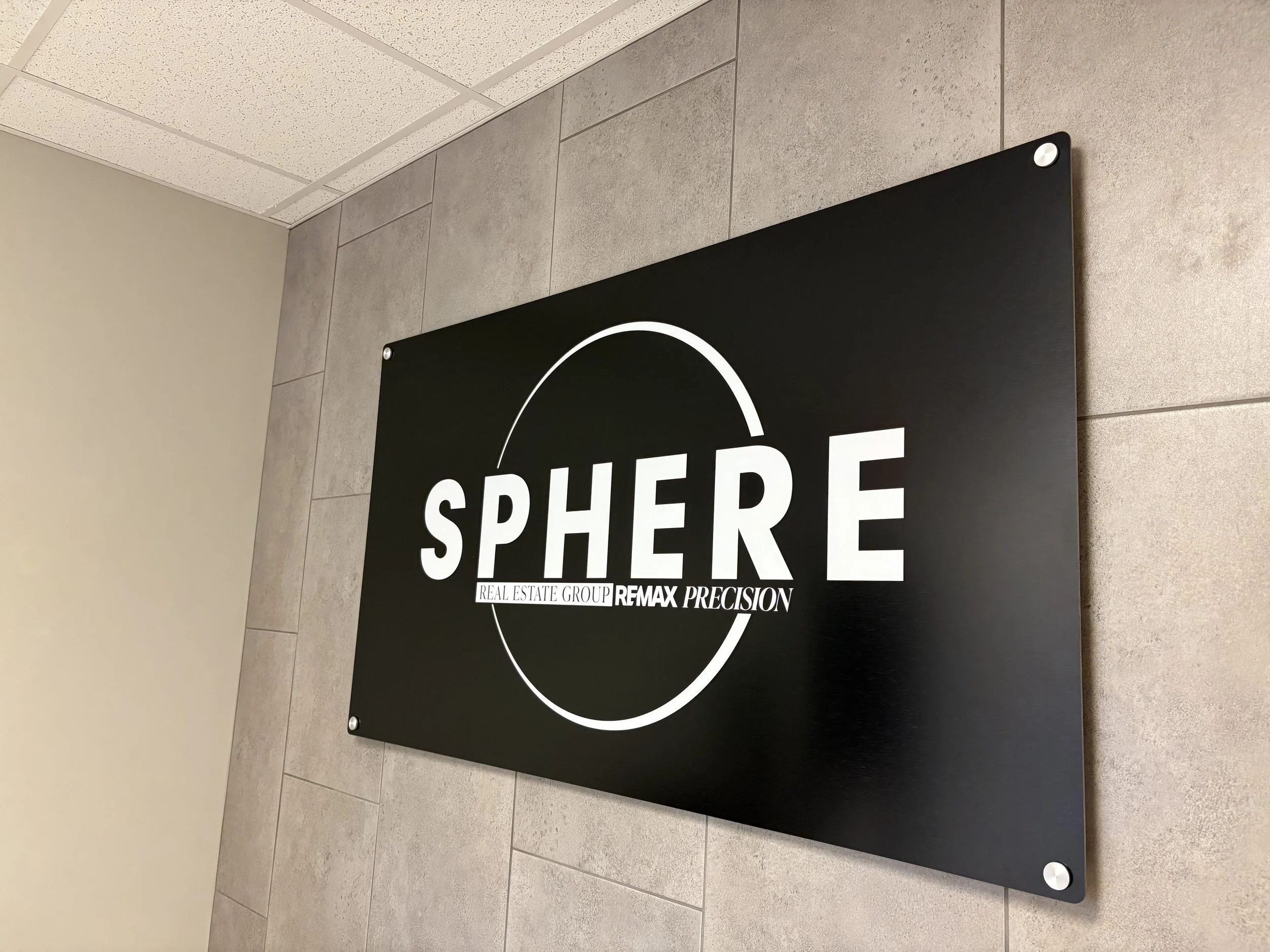A black sign with white text reading 'SPACE' and brand logos, mounted on a tiled wall.