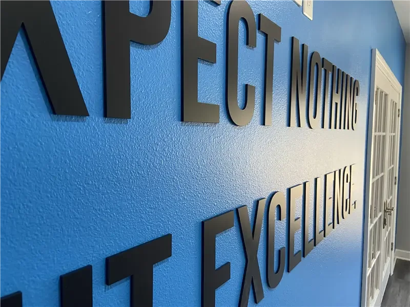 Blue wall with black dimensional acrylic letters saying "EXPECT NOTHING BUT EXCELLENCE."