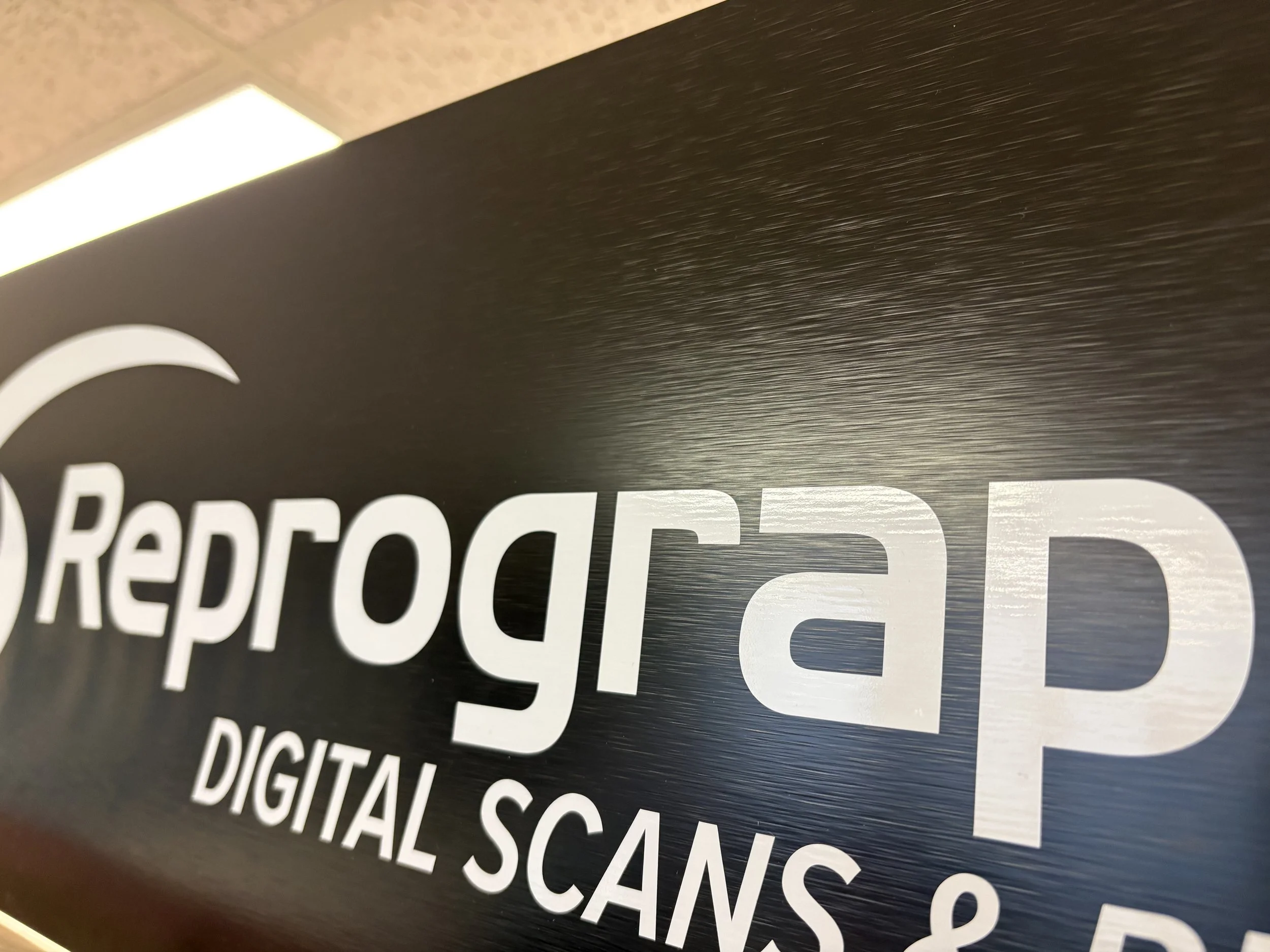 Close-up of a sign with the words 'Digital Signage' and 'Recessed' visible, featuring a black background with white text, and a silver or brushed metal frame.
