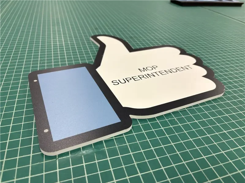 A cardboard cutout of a Facebook 'Like' icon with a thumbs-up symbol, featuring a tablet image on the thumb, and text that reads 'MOP SUPERINTENDENT' inside the thumb.