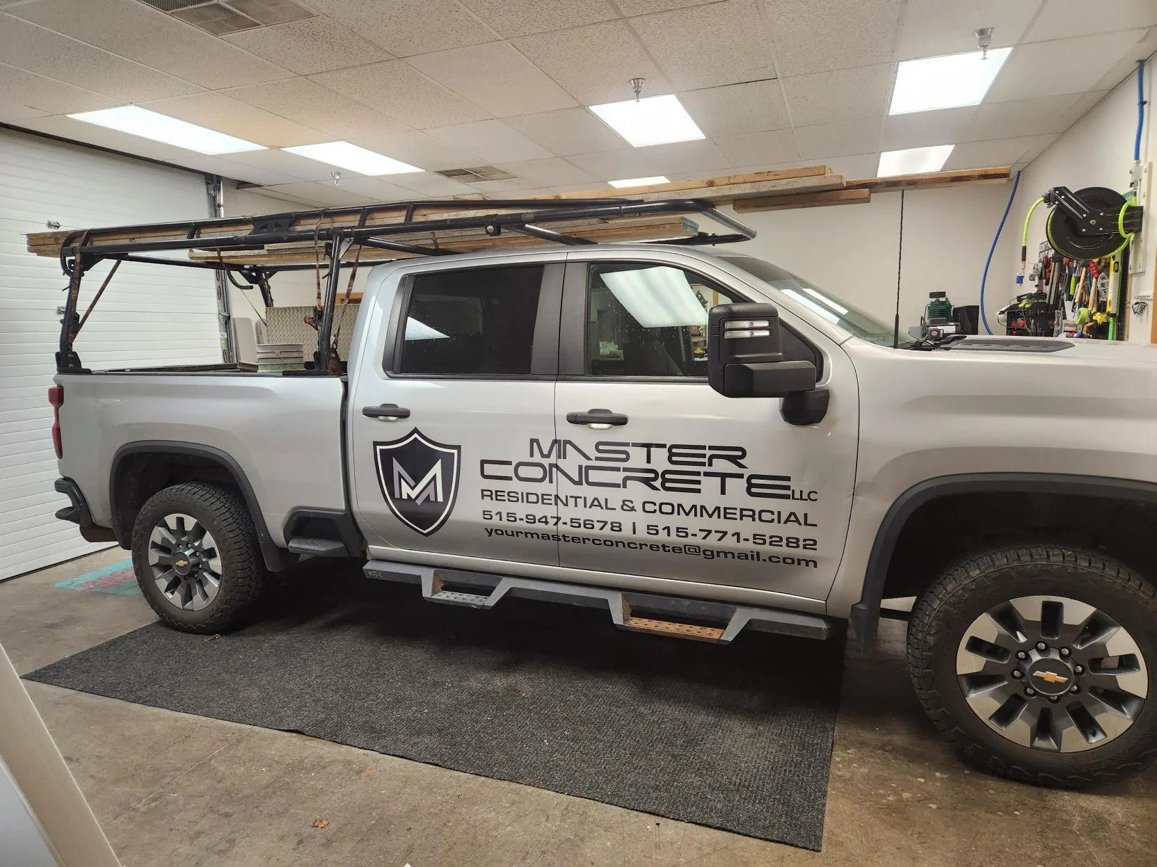 A white pickup truck in a garage with the logo and contact information of Master Concrete LLC on the side.