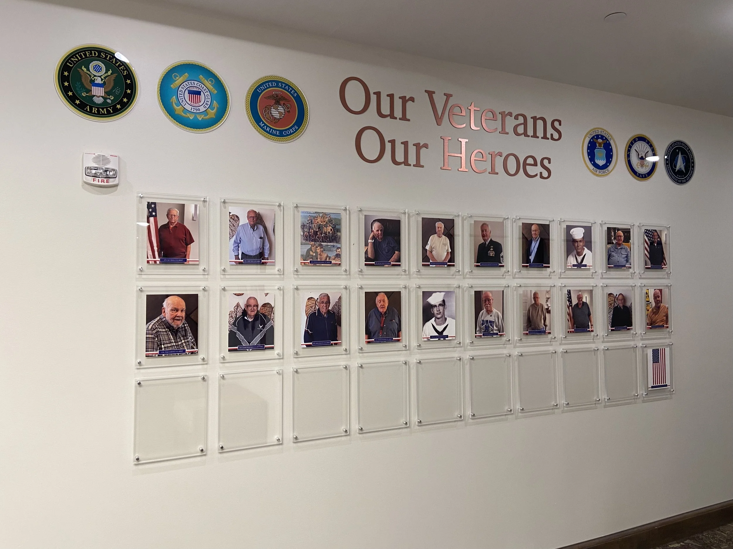 Wall display with photos of veterans and a banner that reads 'Our Veterans, Our Heroes', featuring military service branch logos.