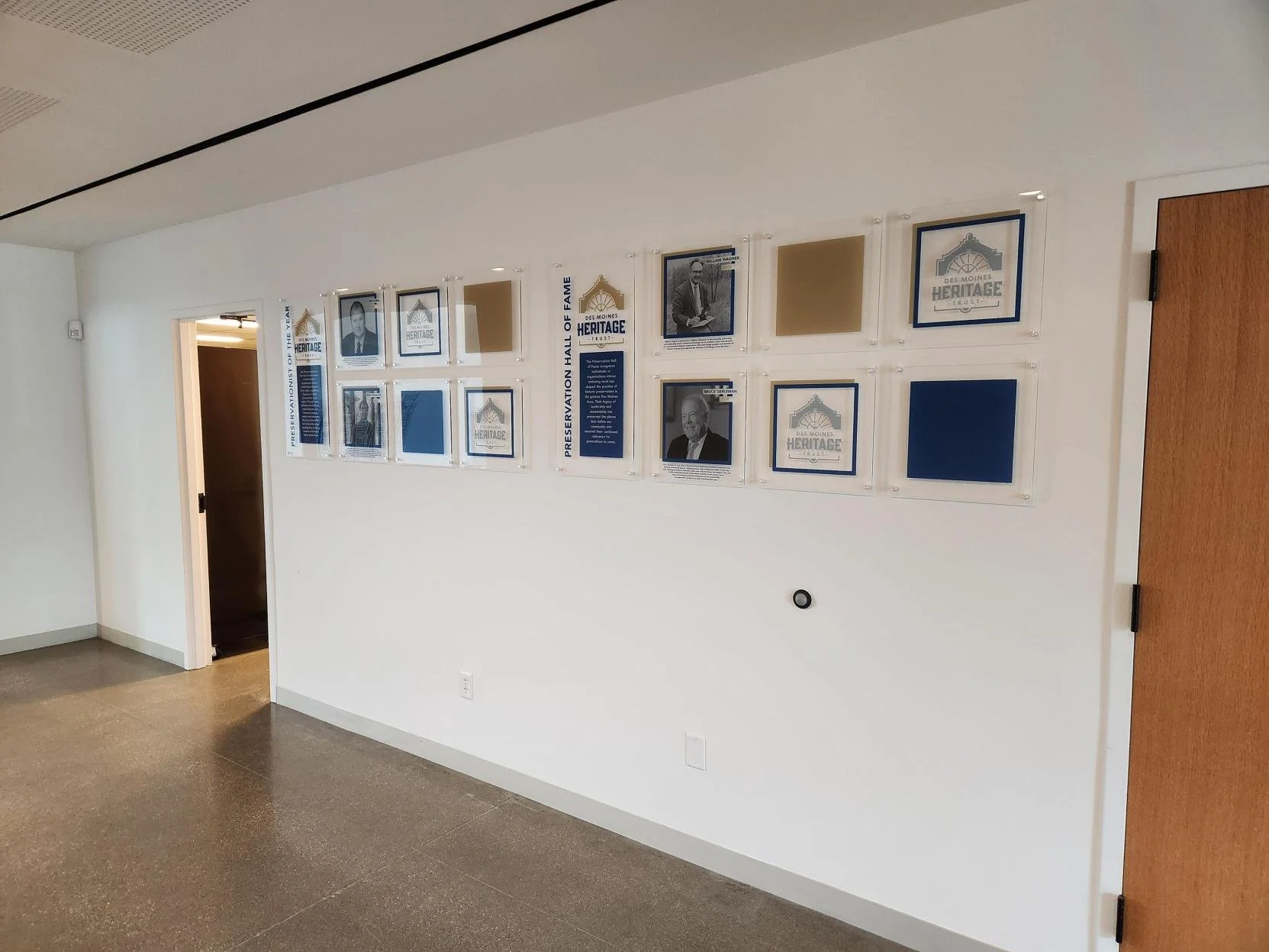 Wall display photographs in acrylic frames, certificates, and icons related to Des Moines Heritage Trust.