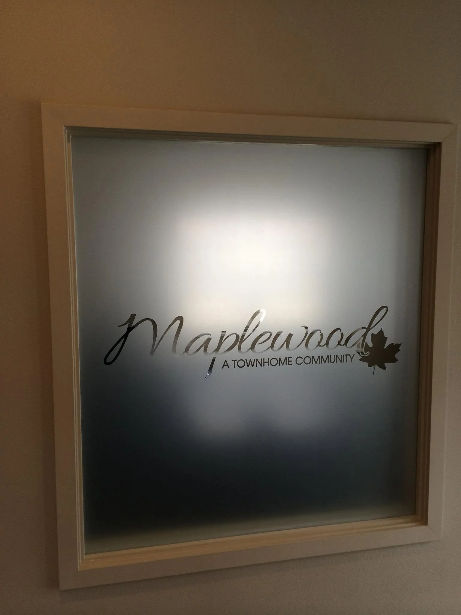 A framed sign on a wall reads 'Maplewood A Townhome Community' with a maple leaf graphic.