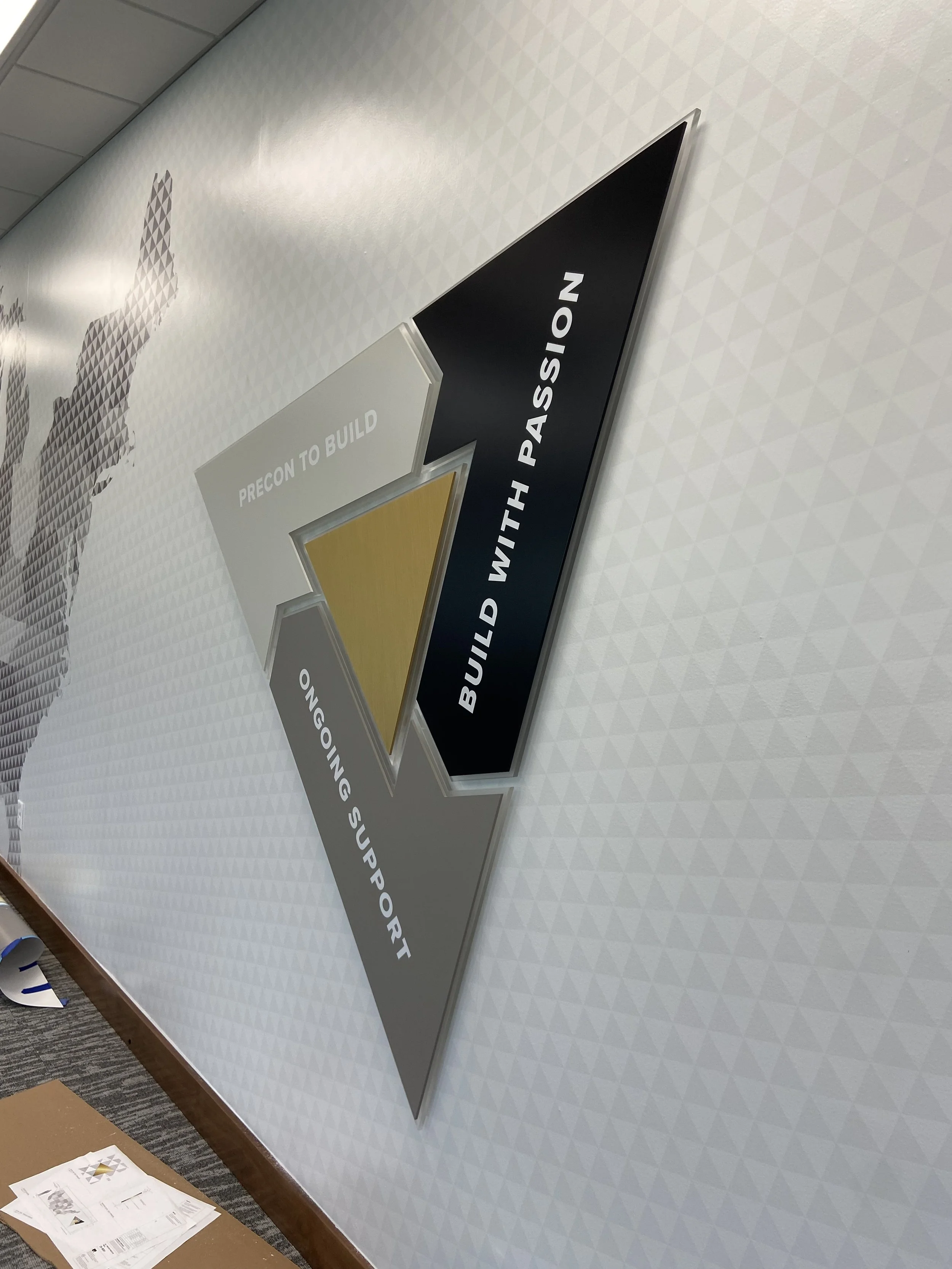  a layered triangle with dimensional pieces in brand colors with brand statements; 'Precon to Build,' 'Ongoing Support,' and 'Build with Passion' in bold letters.