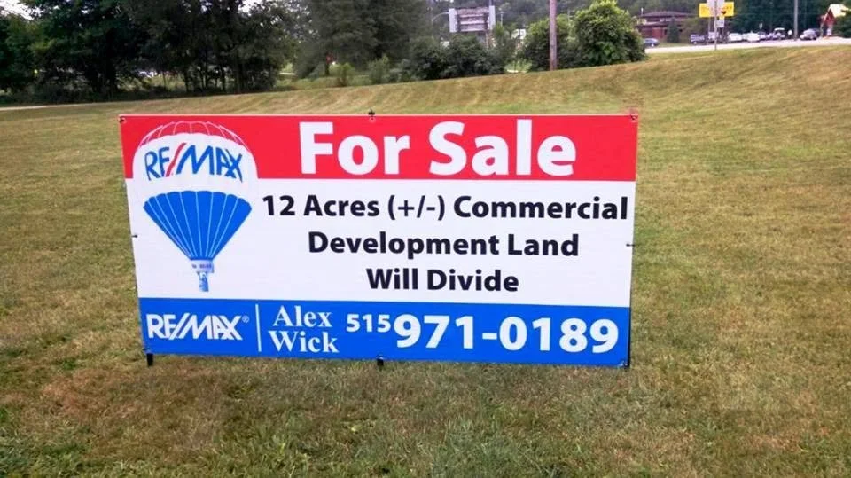 Real estate sign advertising 12 acres of commercial development land for sale, with contact information for Alex Wick