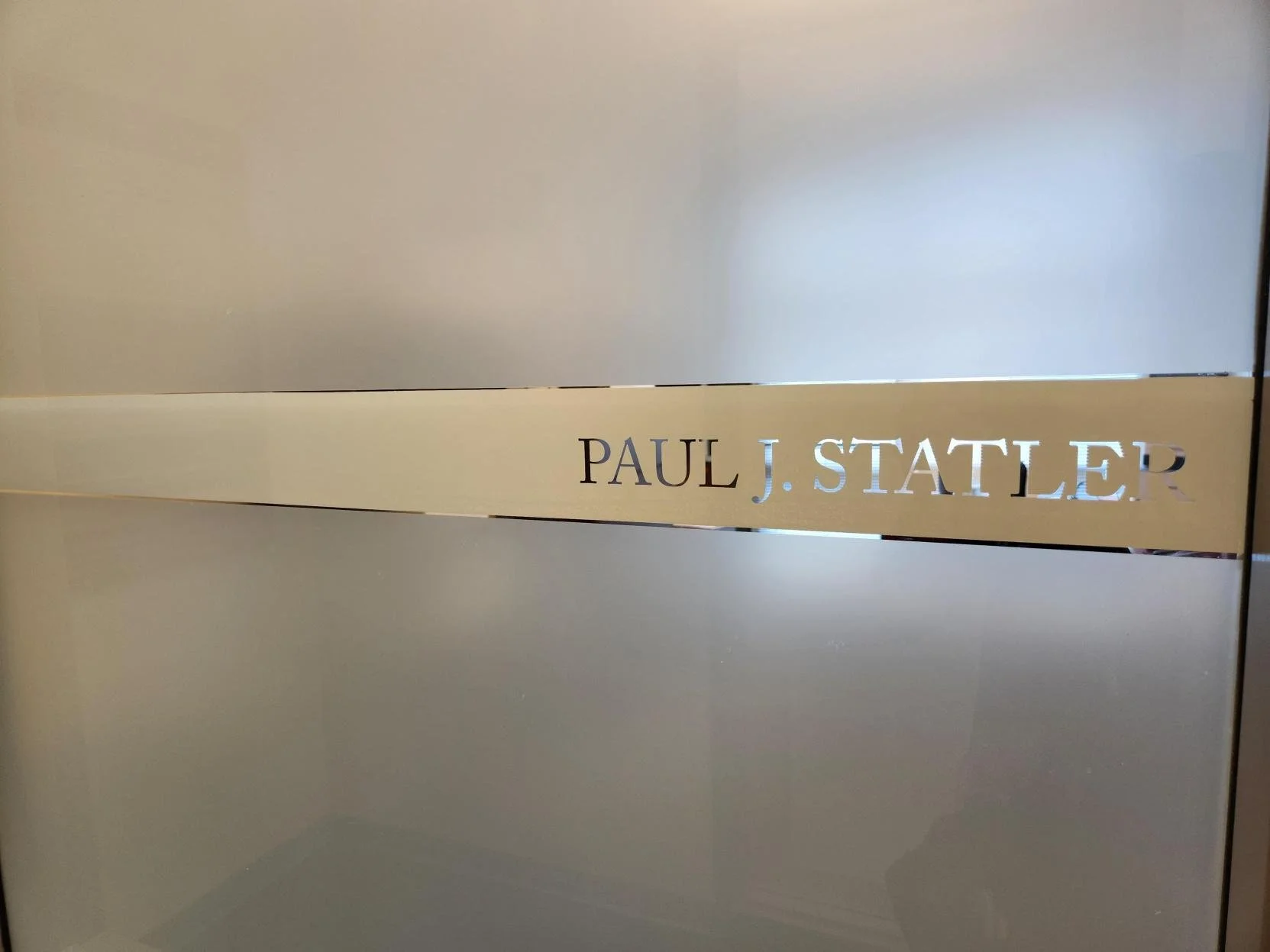 A metallic plaque with cut-out letters spelling 'PAUL J. STATLER'