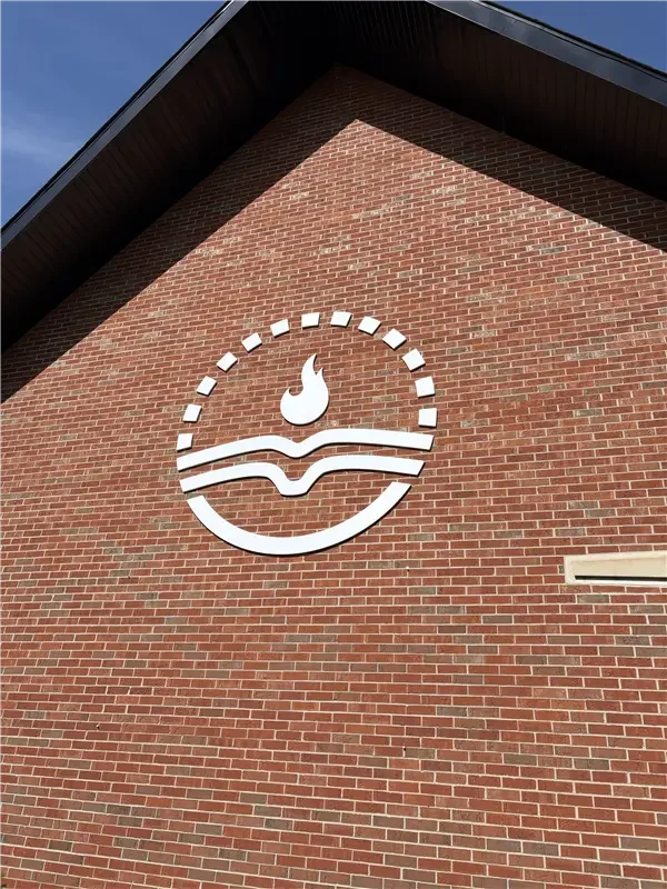 White logo on a red brick wall depicting a hot tub with steam rising above it, inside a dotted circle.
