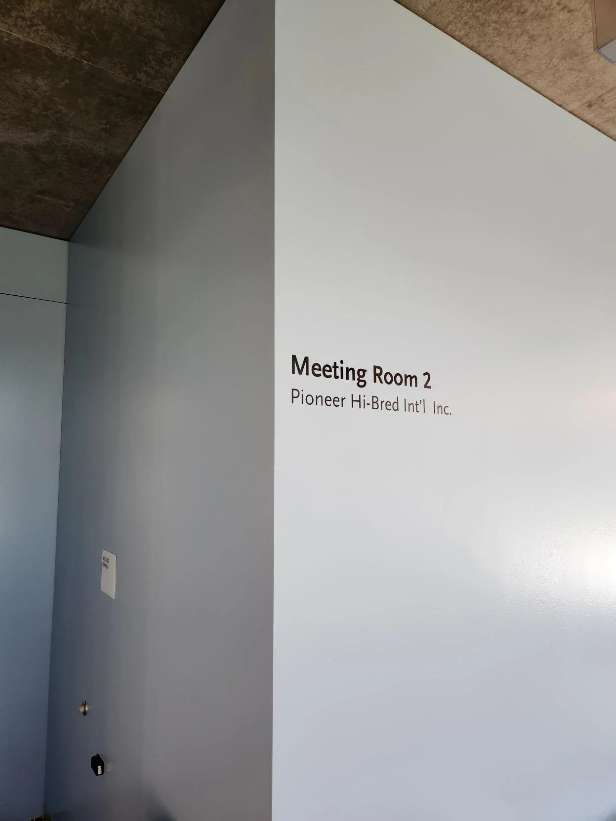 Corner of a wall with a sign indicating 'Meeting Room 2' operated by Pioneer Hi-Bred International Inc.'