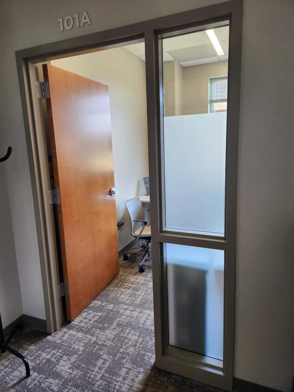Office door labeled 101A is open, showing a room with a desk, office chair, window, and partial view of a frosted glass wall.