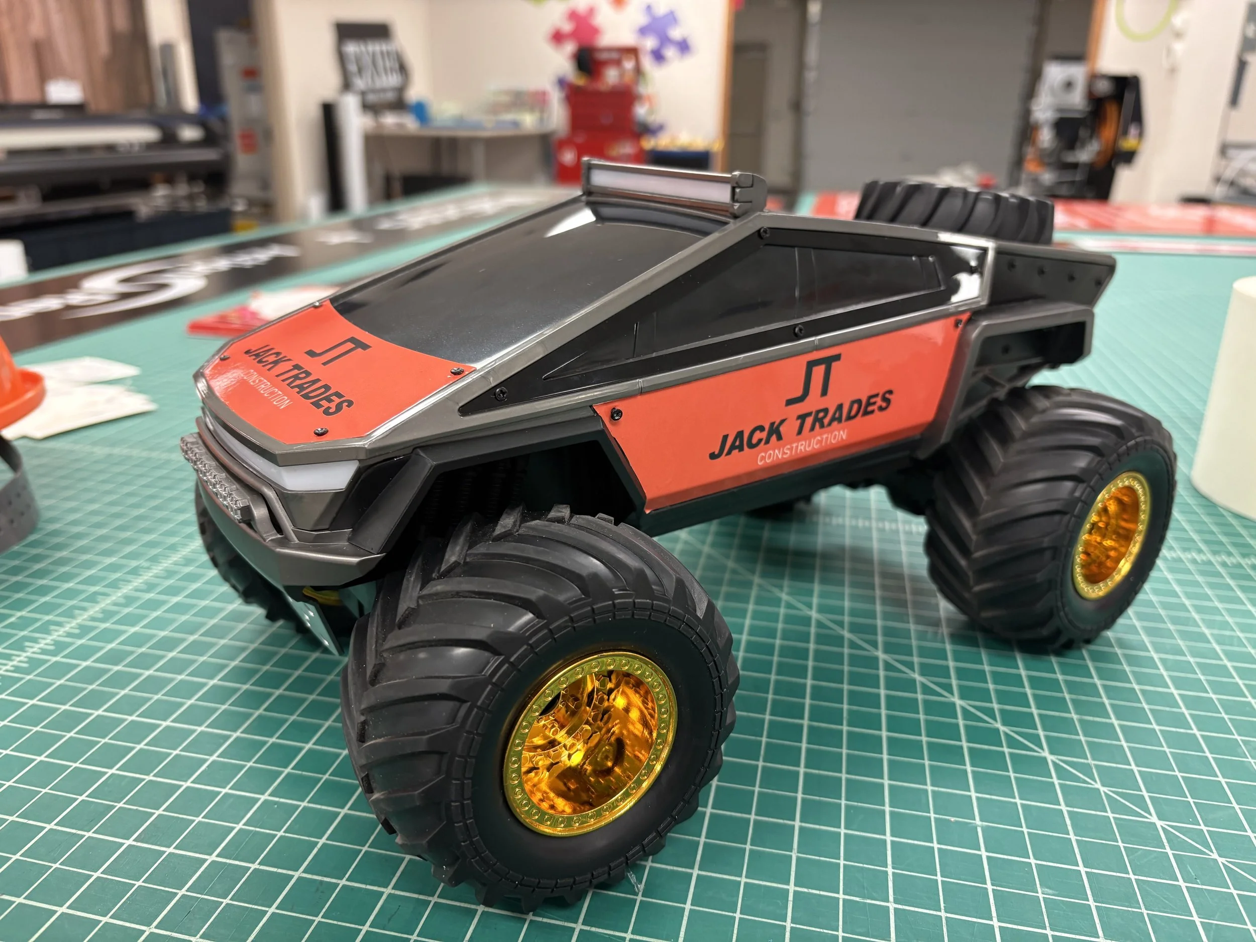 A toy monster truck on a green cutting mat with a workbench and tools in the background.