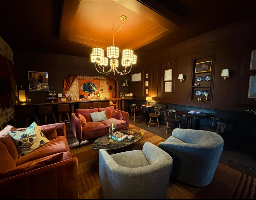 Cozy lounge with leather couches, armchairs, a chandelier, and wall decorations.