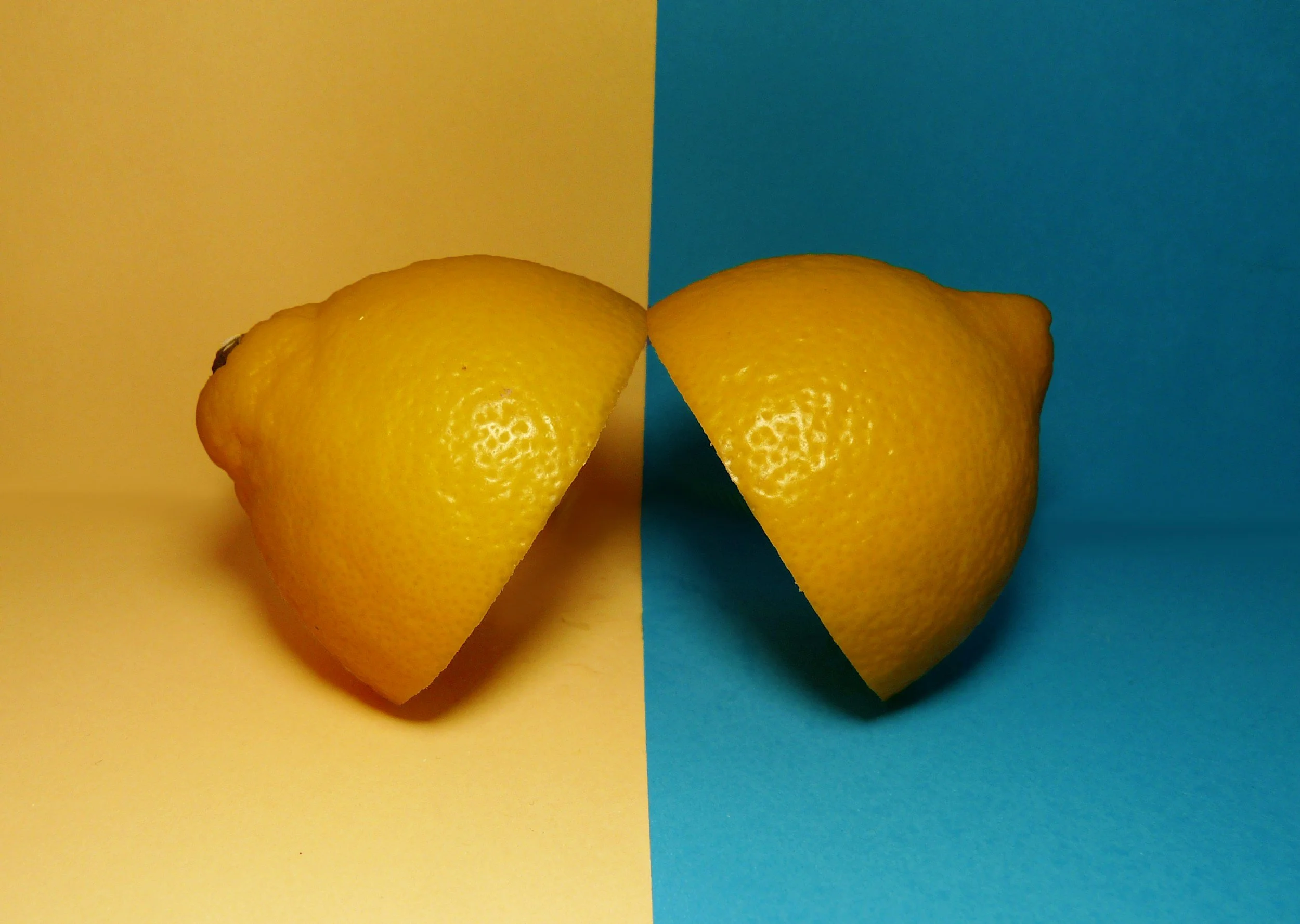 A halved lemon positioned on a split background with yellow on the left and blue on the right.