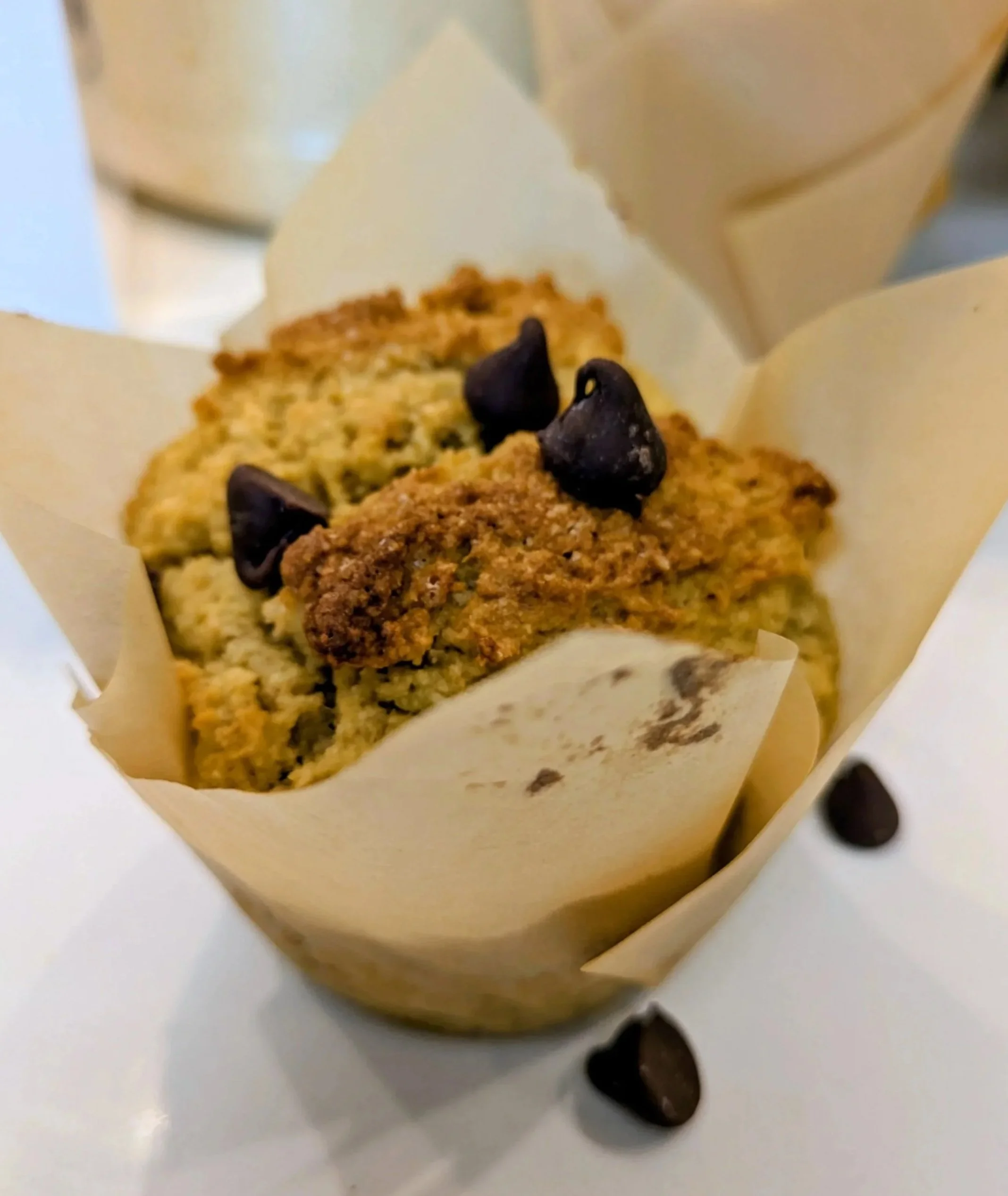 Close-up of chocolate chip cookies in a paper wrapper with chocolate chips on top.