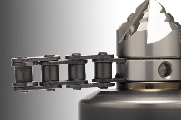 Close-up of mechanical chain link connected to a metallic component with mechanical teeth.