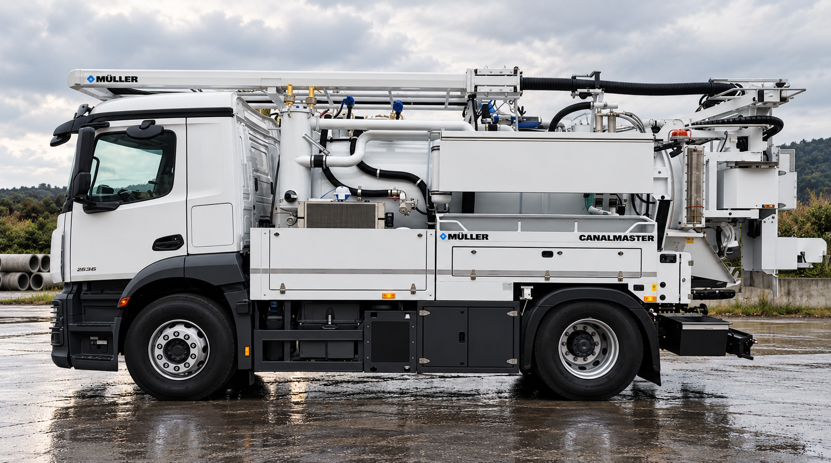 White industrial utility truck with various pipes, tanks, and machinery, branded with 'Müller' and 'CanalMaster' logos, parked on a wet surface outdoors with cloudy sky and trees in the background.