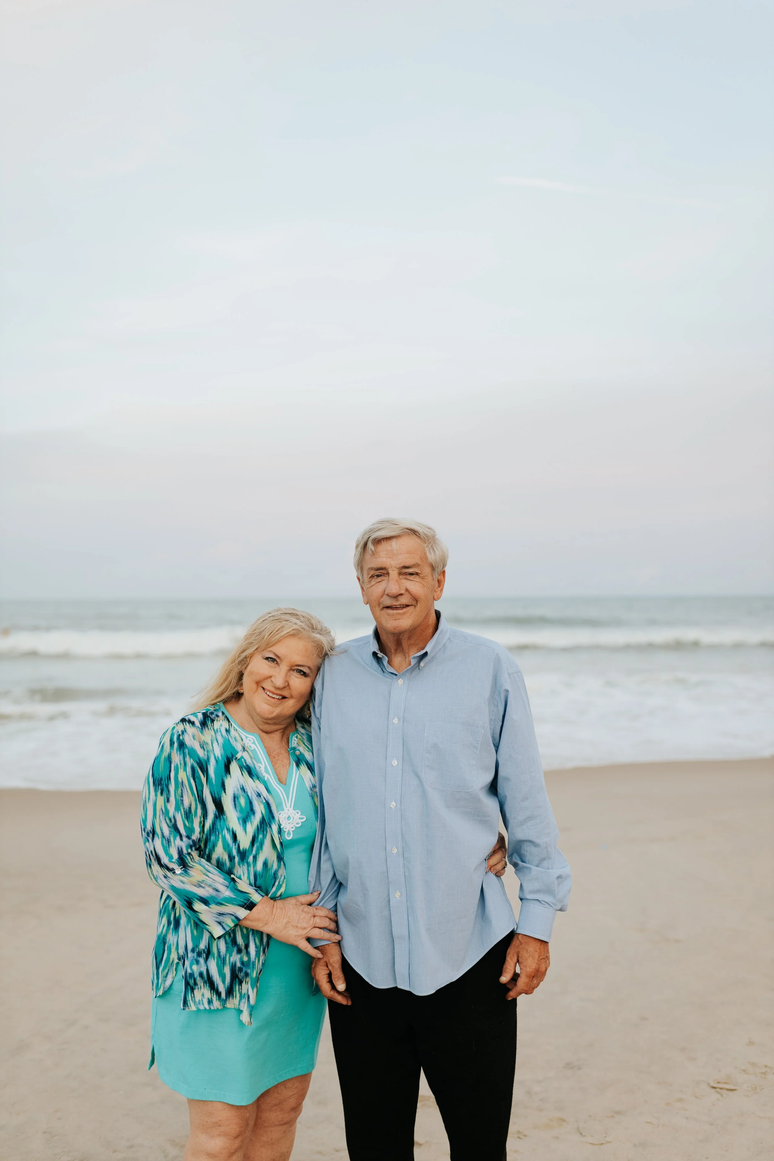 Older couple embracing on a sandy beach with ocean waves in the background