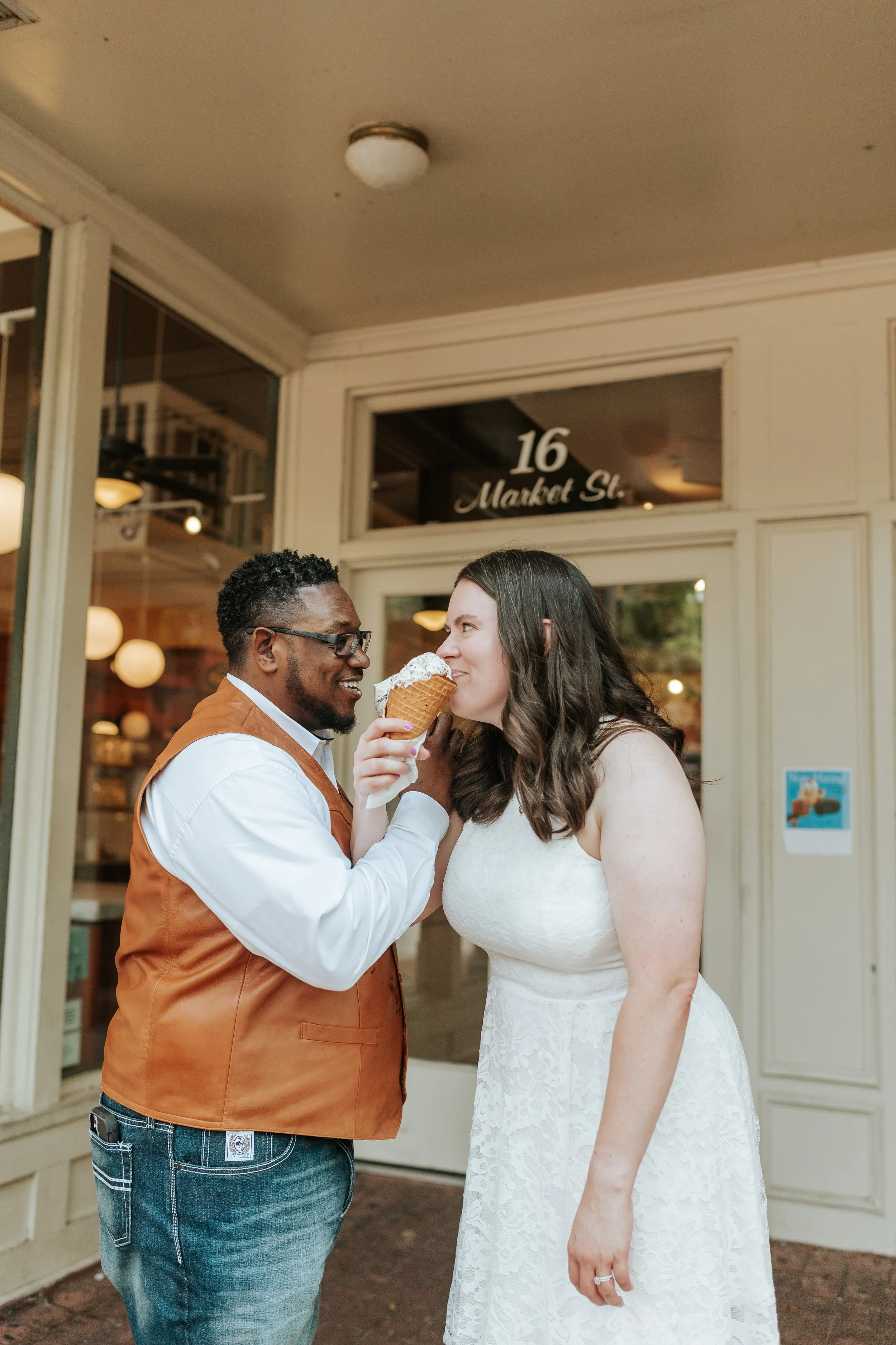 Couple sharing an ice cream cone outside an ice cream shop, with a "16 Market St." sign behind them.