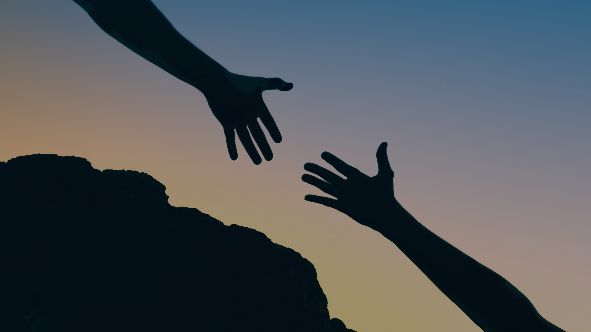 Silhouettes of two hands reaching out to each other at sunset or dusk, with a hill in the foreground.