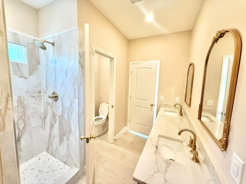 Bathroom featuring a walk-in shower, double-sink vanity, and quartz countertops.