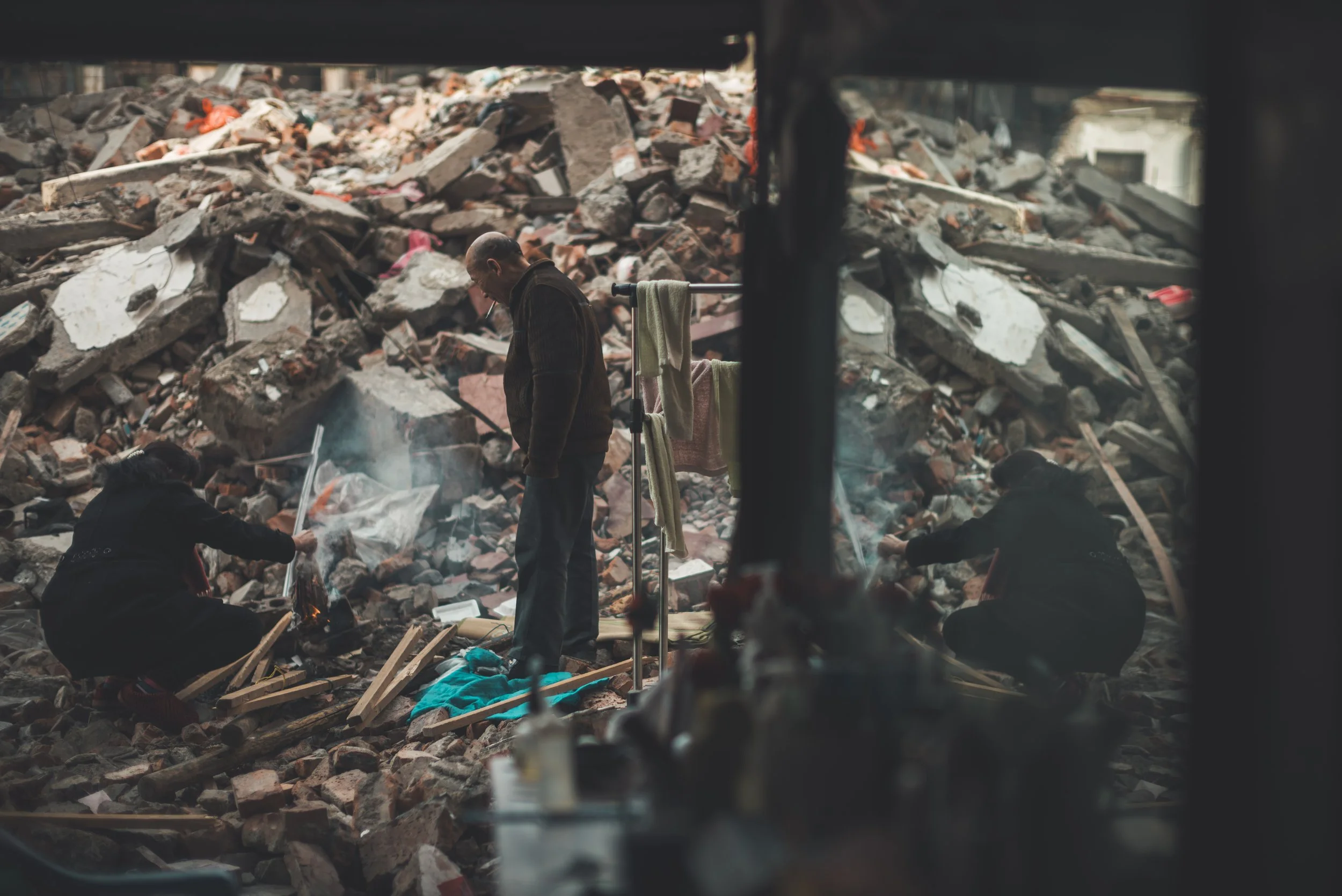 People salvage items from rubble and debris of a collapsed building.