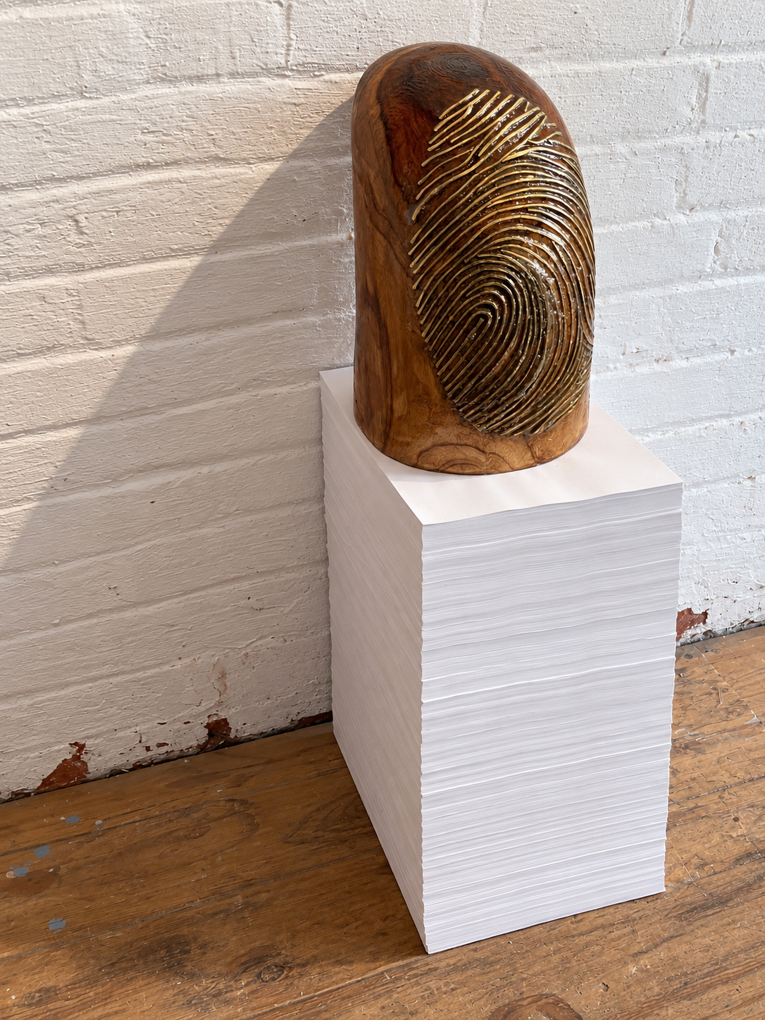 Golden Fingerprint Sculpture on Paper Pedestal.png