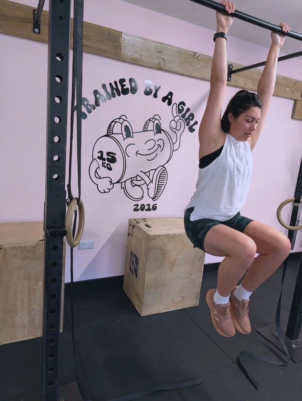 girl holding herself up in front of the trained by a girl logo
