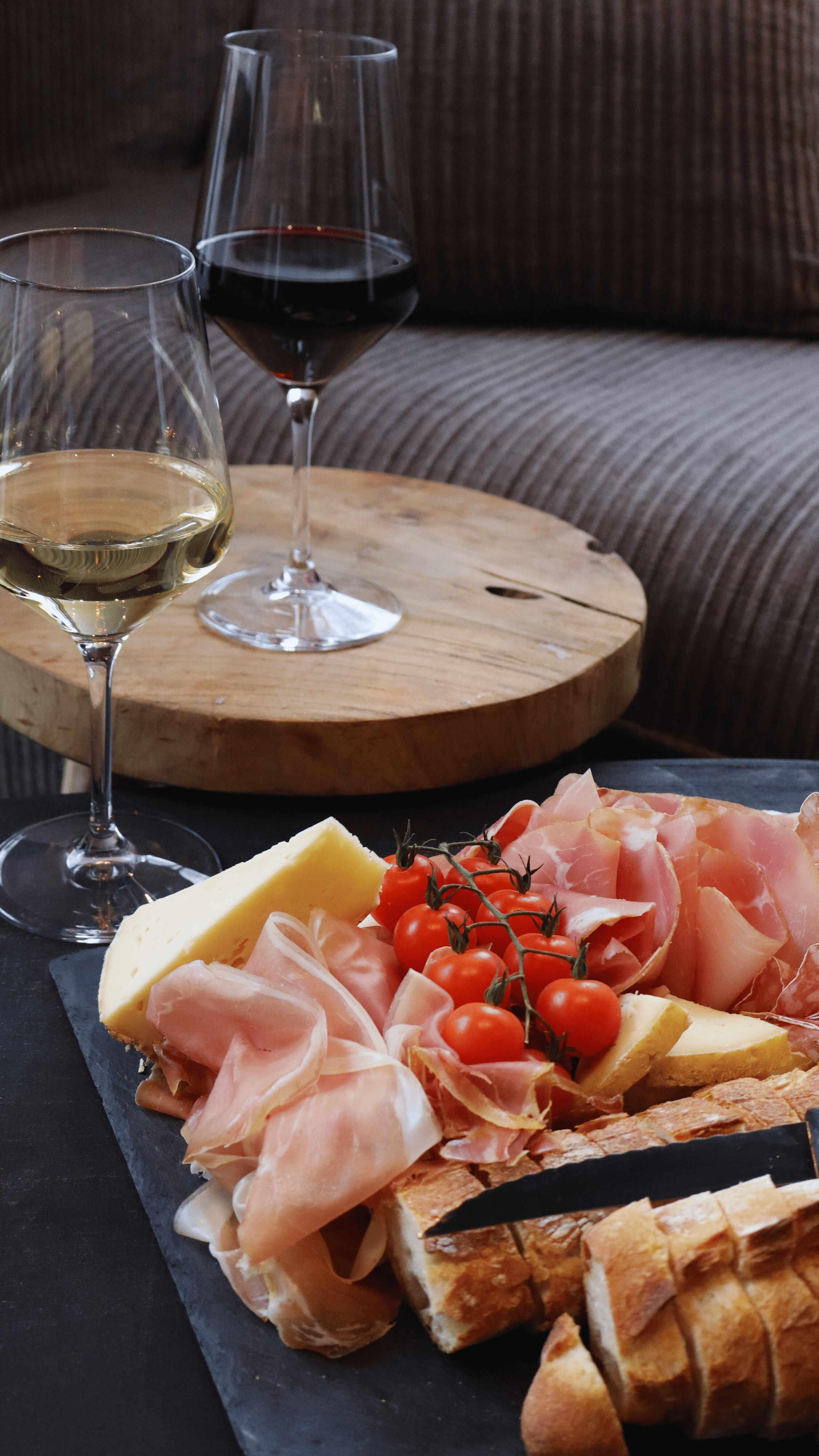 L'ORIGINAL : Une planche de charcuterie avec des tomates cerises, du fromage, du pain et du jambon, accompagnée de deux verres de vin blanc et d'un verre de vin rouge à G.APERO LYON