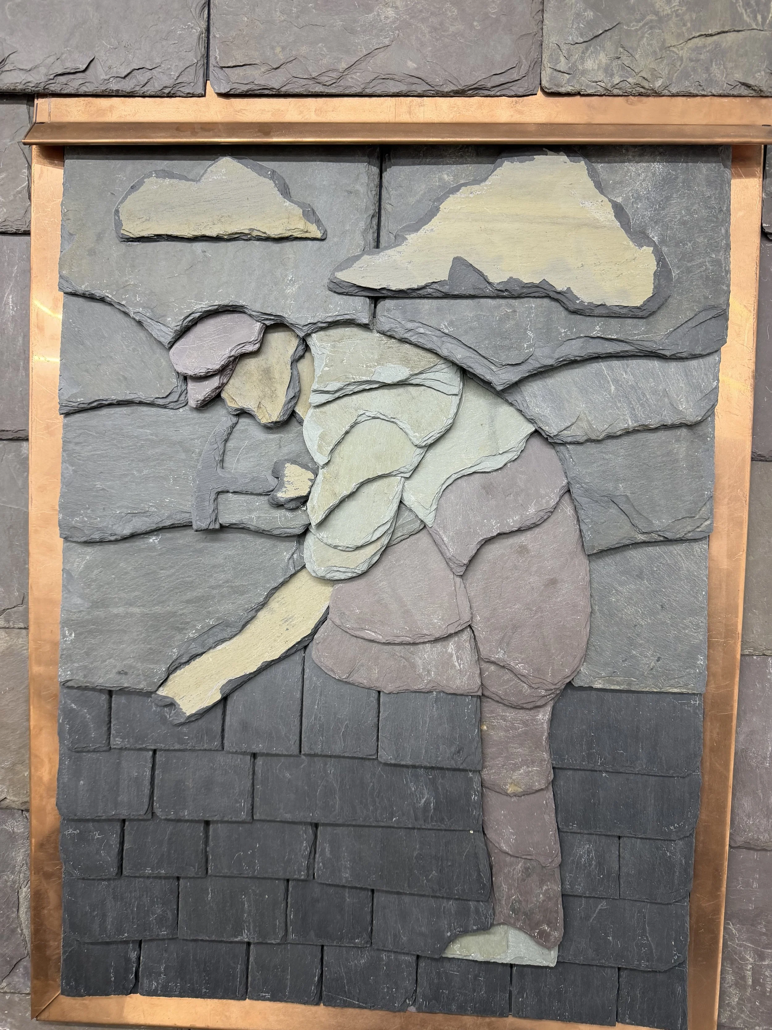 Arranged display of various types of natural stone slabs with diverse colors and textures, framed with a copper-colored border.