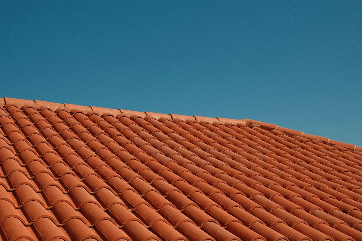 Close-up of a red clay tile roof under a clear blue sky.