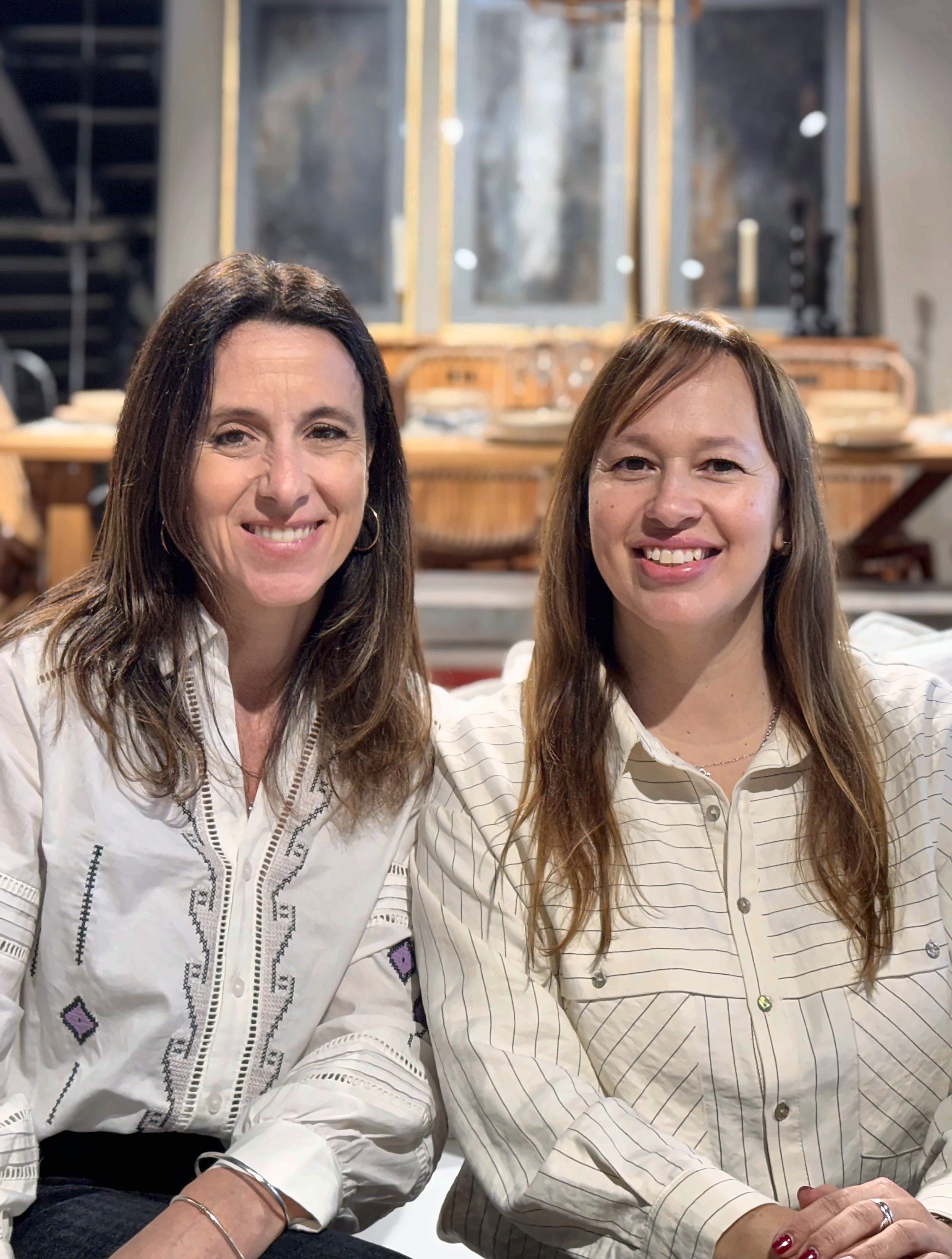 Dos mujeres sonrientes posan para una selfie en un restaurante. Las Socias de Estudio Leve.