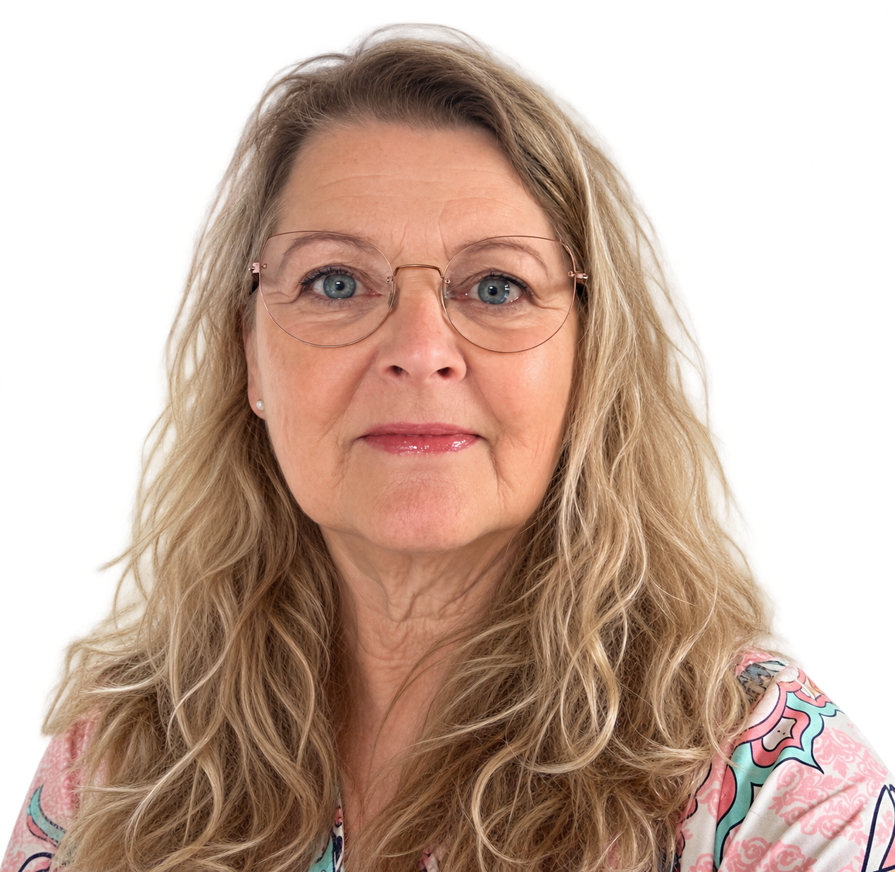 Portræt af en kvinde med blond, bølget hår, briller og let makeup, iført en farverig, mønstret bluse.