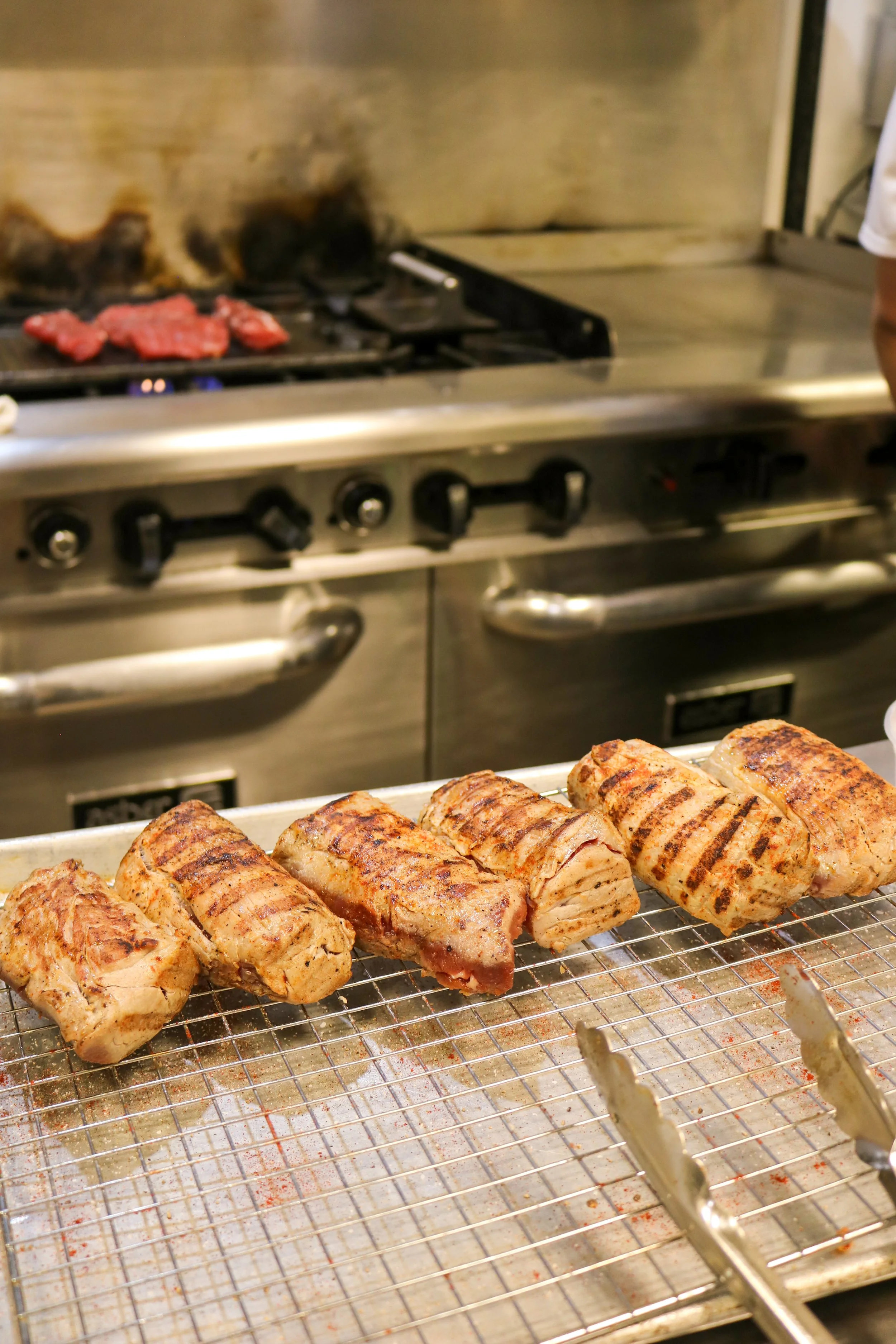 Grilled meat and skewers in a commercial kitchen or restaurant setting.
