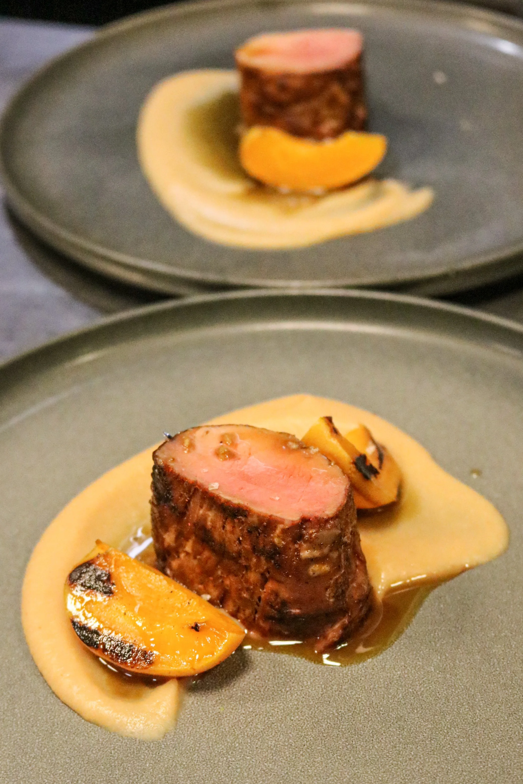 Seared filet mignon topped with a slice of foie gras, served with a roasted peach half, all on a bed of creamy sauce.