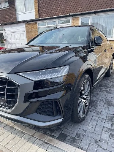 Black luxury SUV parked on a driveway in front of a house.