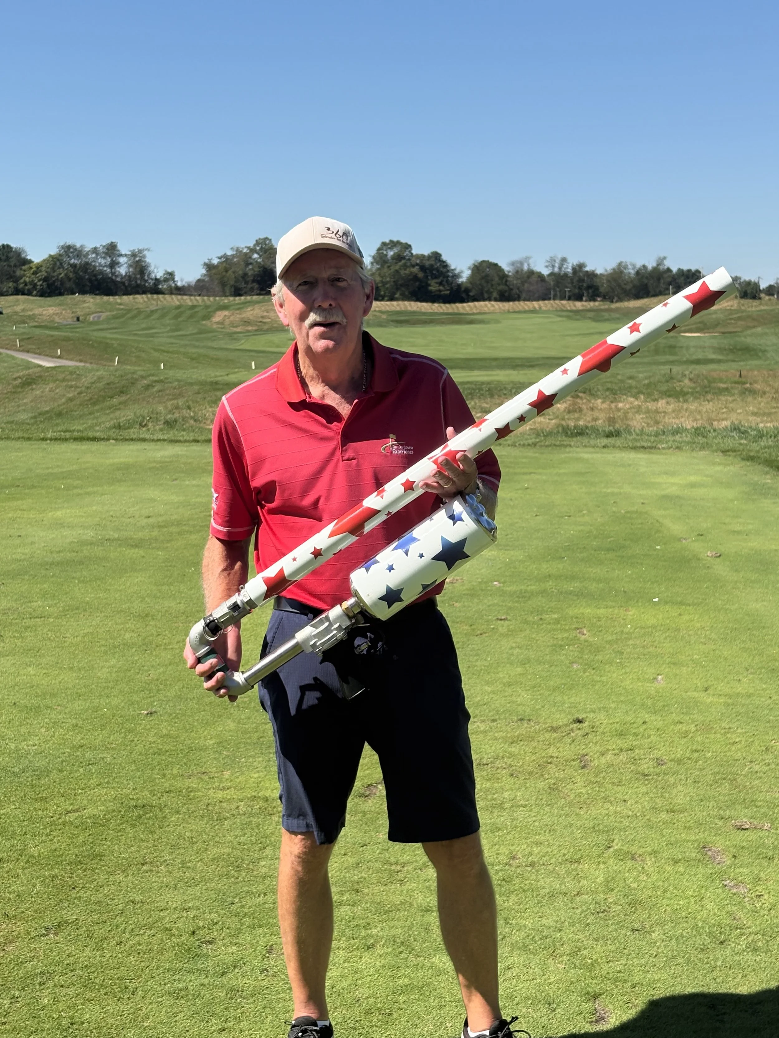 “On Course Experience team member holding a golf ball air cannon at a Maryland golf tournament.”