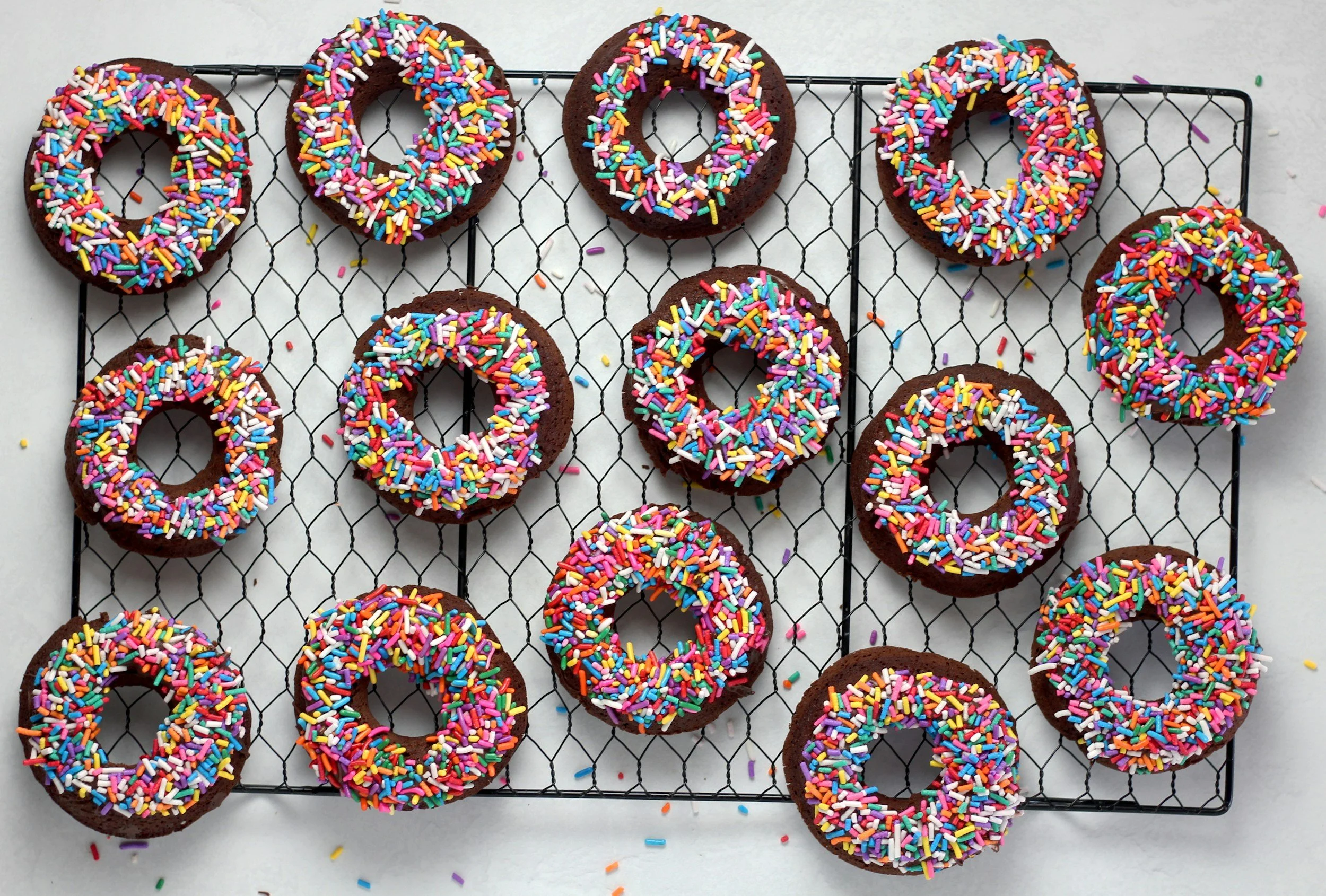 Sprinkle donuts cooling on a wire rack