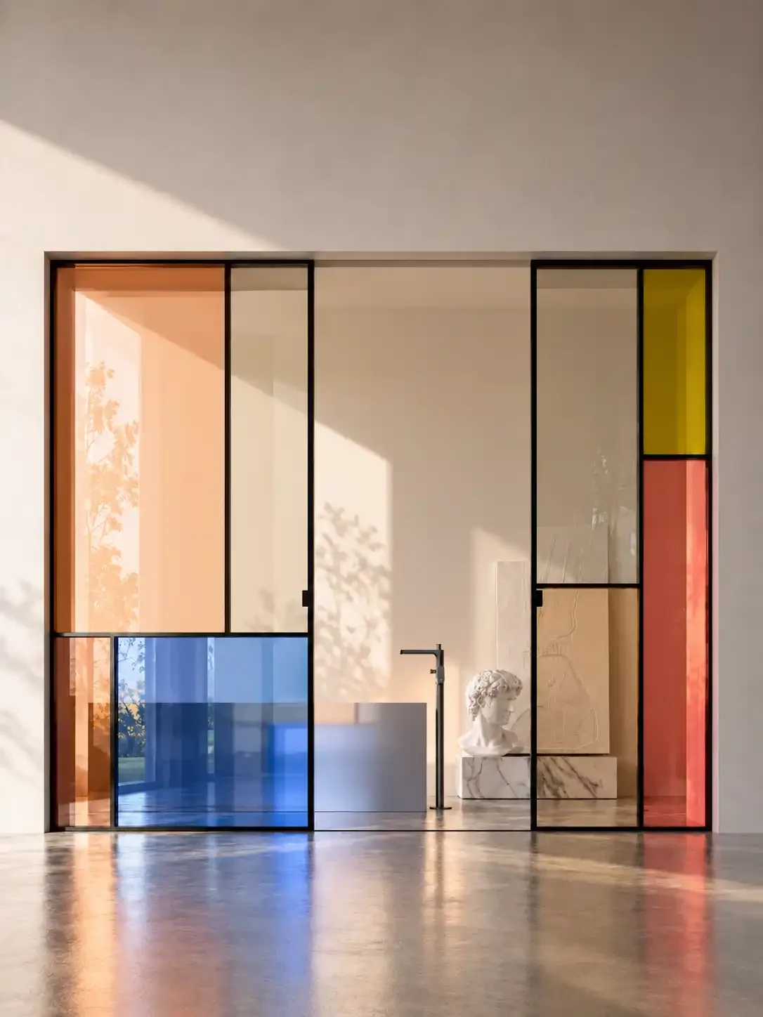Modern art installation with multicolored glass panels and a classical marble bust sculpture.