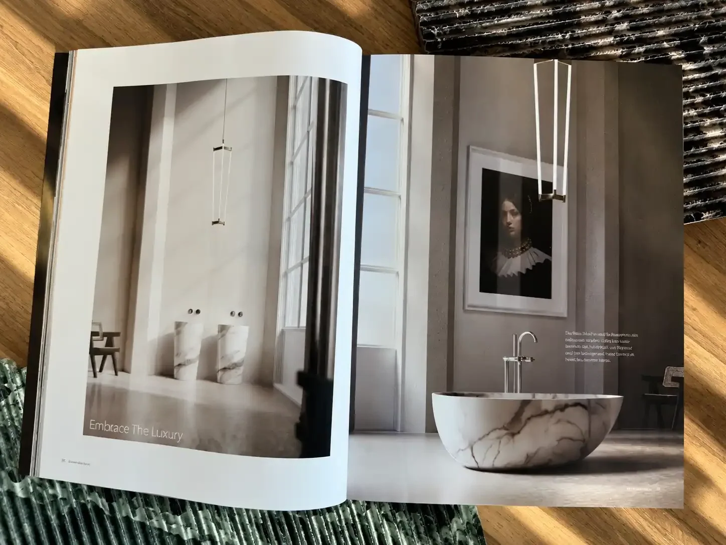 Open magazine showing a luxurious bathroom with a freestanding marble bathtub, large windows, and contemporary artwork on the wall.