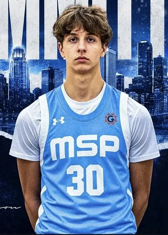 Young male athlete with short, curly brown hair wearing a blue and white sports jersey with the number 30 and MSP logo, standing in front of a cityscape background.