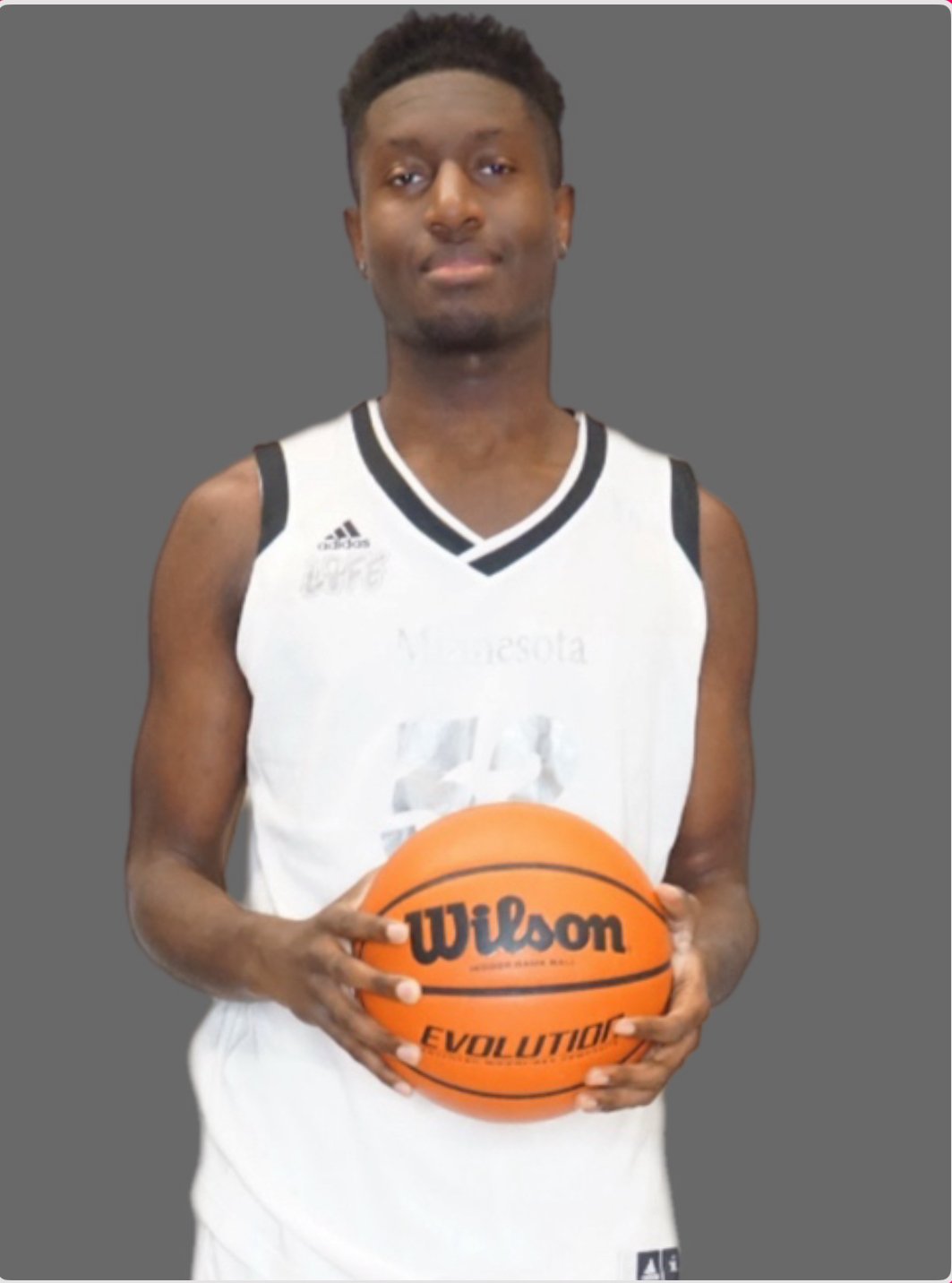 A young man in a white basketball jersey holding a Wilson basketball