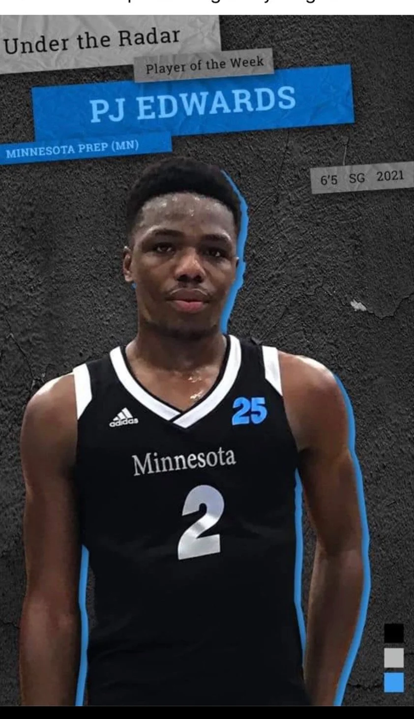 A young male basketball player in a black Minnesota jersey with the number 2 and a blue 25, standing against a black textured wall, sweaty and looking at the camera.