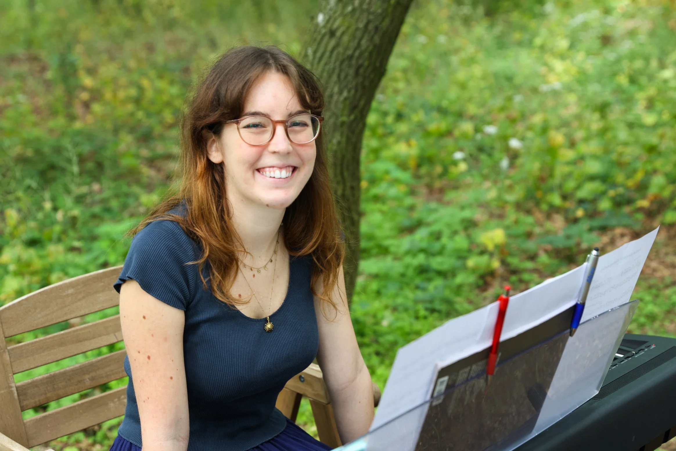 Smiling woman outdoors in the nature besides a piano and sheet music at a wedding ceremony