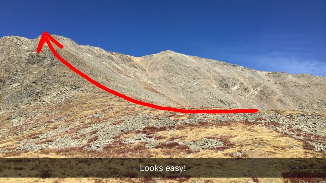 A mountain with a red arrow drawn over a steep slope indicating a climbing or hiking path, with a caption that says 'Looks easy!'