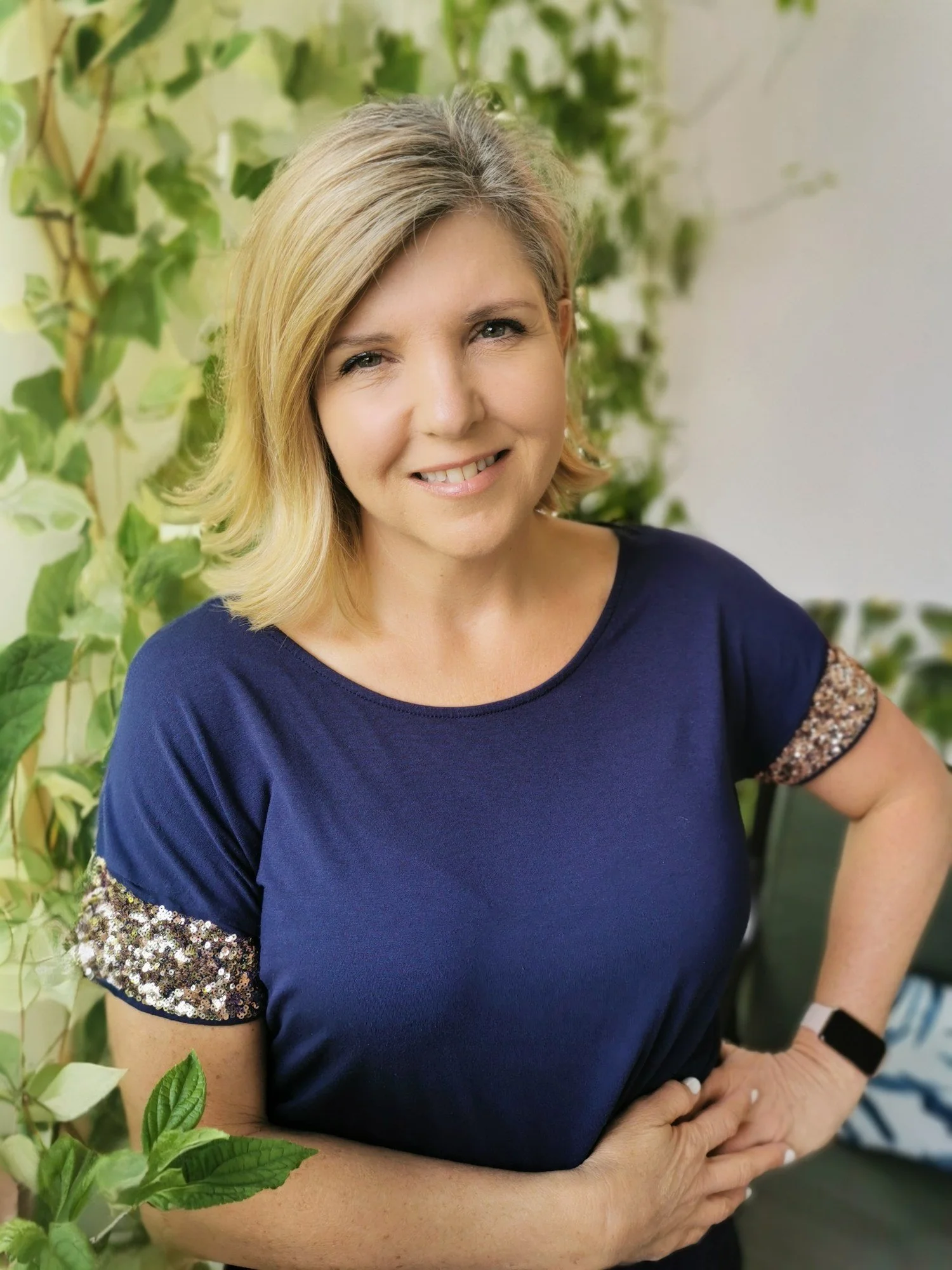 Karen Lantigua, travel advisor, smiling in a navy top in front of green plants